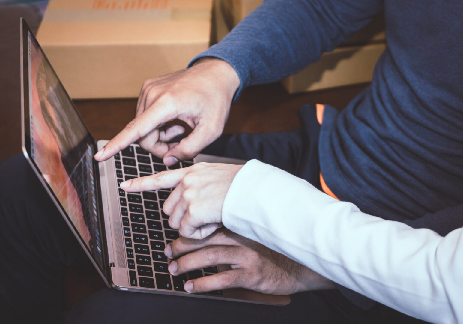 Two people pointing at a laptop screen discussing something.